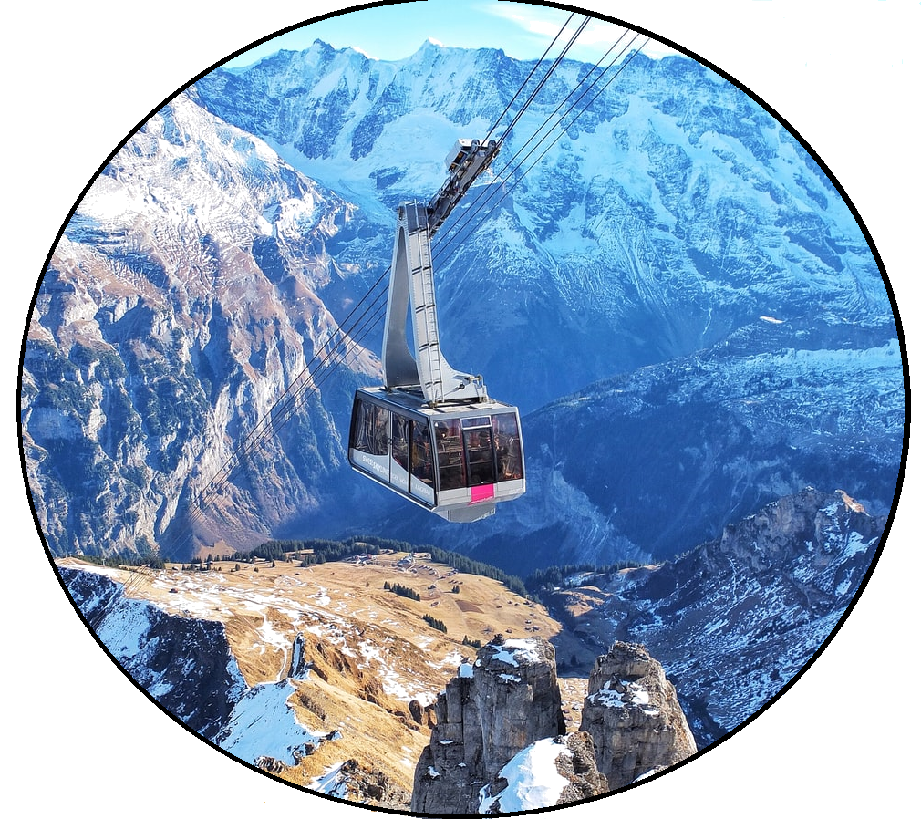 Taking Everyone to the Top A large glass aerial tram ascends to the top of snow-covered, dazzling mountains on a clear day