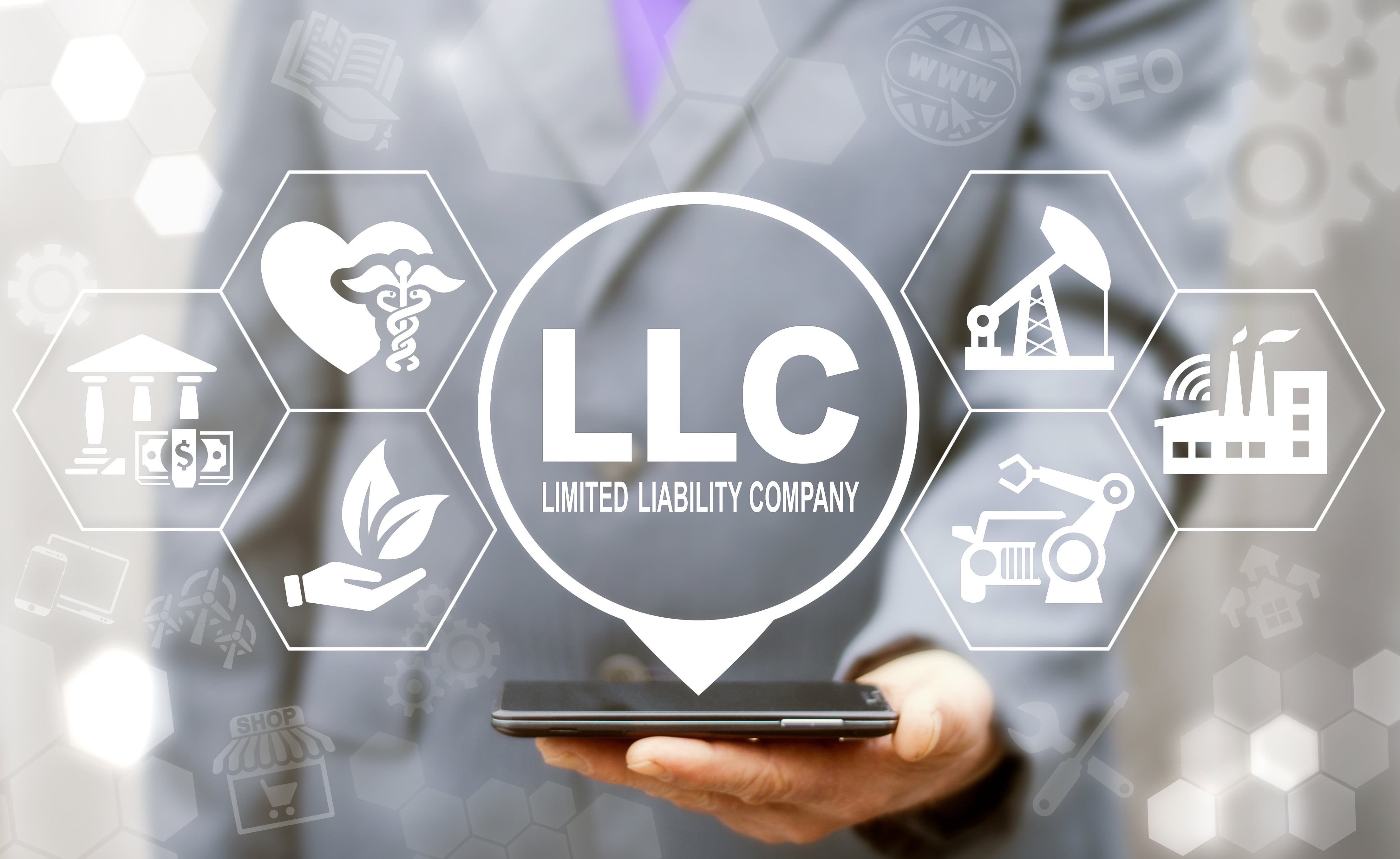 A business man, faded into the background, in a gray suit holds a smart phone with LLC, Limited Liability Company, projected above, while icons for various other industries surround it.