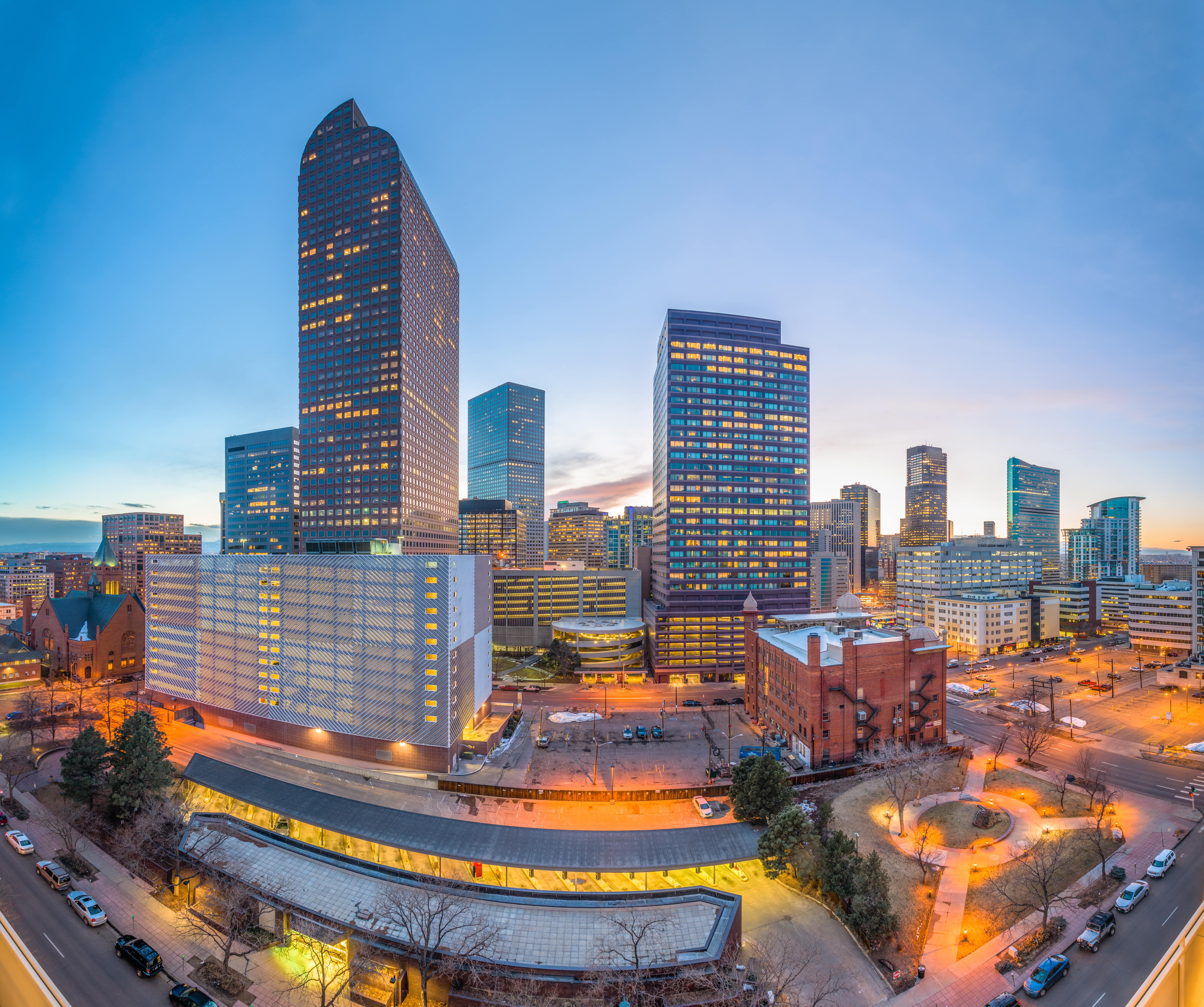 Downtown Denver, Colorado at sunset centered on the Wells Fargo Center with the Central Presbyterian Church on the left as the city buildings begin to light up, photo was shot from a fisheye lens.