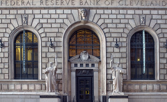 Image of the front of the Federal Reserve Bank of Cleveland - a beautiful stone building with gray statutes on each side of a black door.