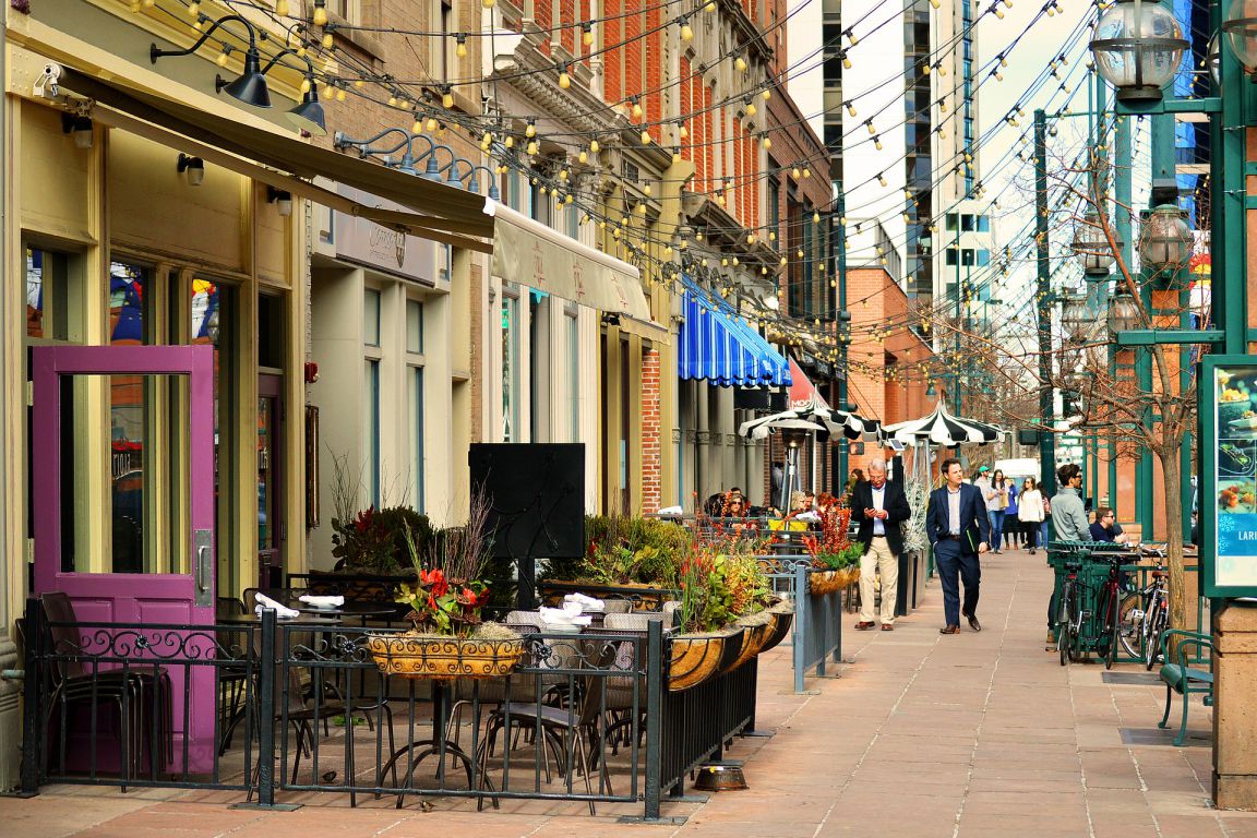 Elegant small business storefronts lining Larimer Square in downtown Denver, Colorado, with strings of lights hung above as people walk about and shop.