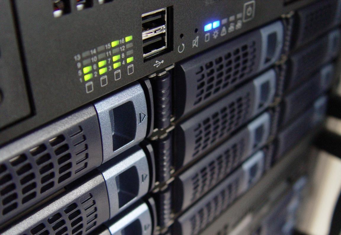 a close-up image of the front of a black server panel with hot-swappable hard drives, the blue and green system lights indicate the system is in great shape.